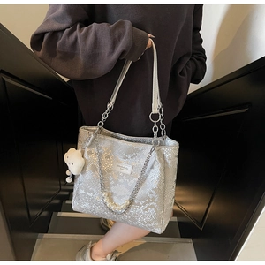 Detail of silver snake-pattern tote bag with pearl charms and white plush pendant