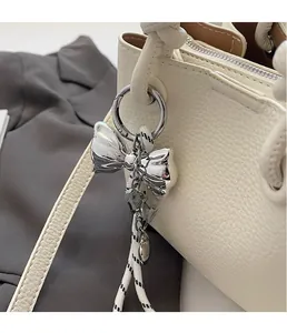 Macro shot of a silver bow metal charm with black and white woven rope on a bucket bag