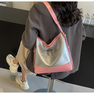 Detail shot of a pink and silver shoulder bag with a metallic bow clasp and leather strap