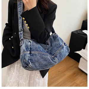 Detail of retro washed denim crossbody bag featuring heavy texture and wide strap