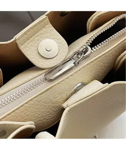 Detail of silver zipper and magnetic clasp on cream bucket bag with lychee texture