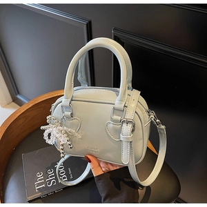 Detail of light blue Boston bag with leather texture and heart-shaped strap rings