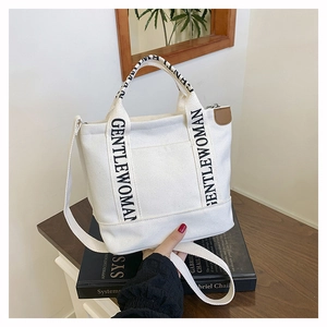 Detailed view of white canvas tote bag with black letter print on handle strap