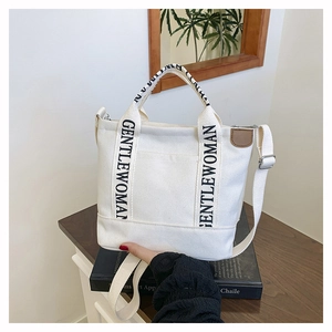 Detail of canvas tote bag with logo straps and front pocket on wooden table