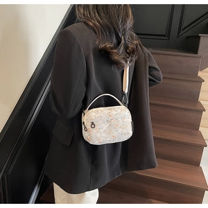 Detail of floral lace embroidery on cream mini crossbody bag with black woven label