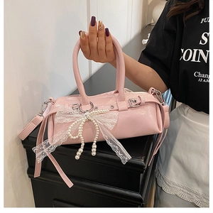 Dettaglio della borsa cilindrica rosa con fiocco in pizzo e decorazioni di perle fini