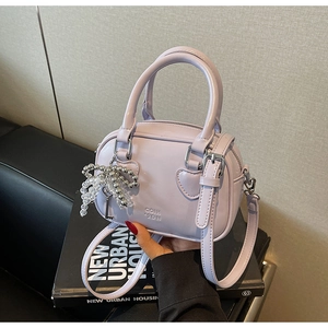 Detail of light purple PU leather handbag with heart stitching and beaded bow charm