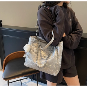 Detail of silver snake pattern tote bag with pearl chain strap and plush charm