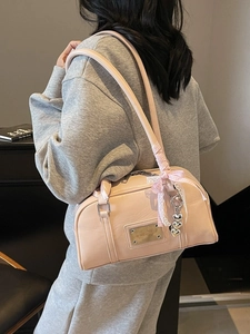 Pink shoulder bag with pillow shape and decorative heart charm for stylish summer commute
