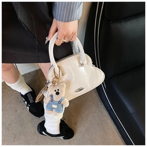 Detalle de bolso de charol blanco con un lindo accesorio de peluche de oso de peluche