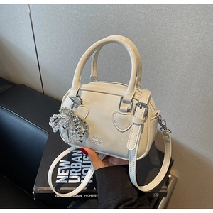 Detail of white patent leather bowling bag with heart patches and pearl charm