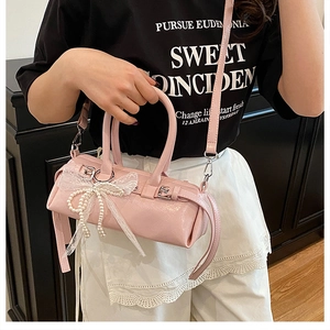 Dettaglio della borsa a cilindro rosa con fiocco di perle e inserti in pizzo bianco