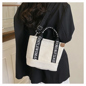Detail of the cream canvas tote bag with black Gentlewoman printed strap and side leather trim