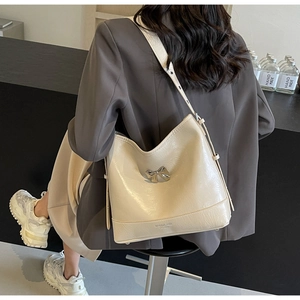 Detail of beige wrinkled leather shoulder bag with a metallic bow and side profile view