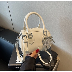 Detail of white Boston bag with heart leather patch and silver beaded bow charm