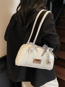White bowling shoulder bag with ribbon bows and heart charm on a black suit model