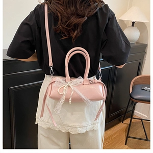 Borsa a cilindro in vernice rosa con fiocco di pizzo bianco indossata dalla modella
