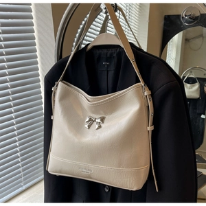 Close-up of off-white wrinkled leather shoulder bag featuring a silver metal bow detail