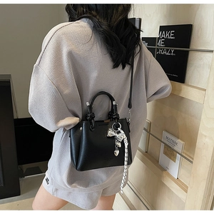 Litchi pattern bucket bag with silver bow charms and woven strap on a stylish model