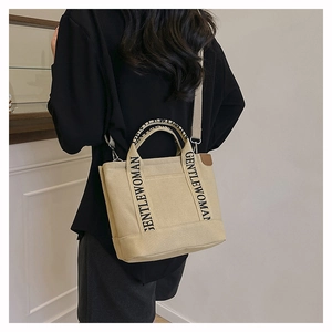 Detail of beige canvas tote with GENTLEWOMAN strap and detachable shoulder belt