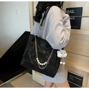 Detail of black snake pattern tote bag with pearl chain and cloud plush charm