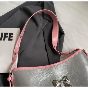 Detail of silver metallic textured shoulder bag with pink strap and metal bow