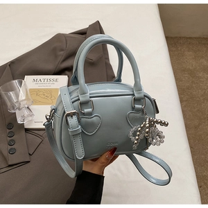 Close-up of light blue leather handbag featuring heart-shaped handle joints and metallic charms