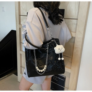Detail of black snake-pattern tote with silver chain, pearls and cloud plush charm