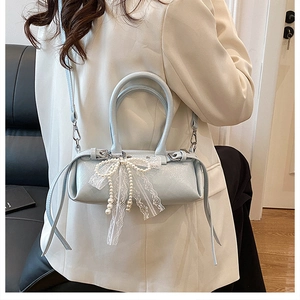 Dettaglio della borsa a cilindro azzurra con perle eleganti e fiocchi in pizzo fine