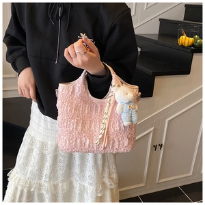 Détail du sac seau rose avec texture plissée et pendentif ours en peluche blanc