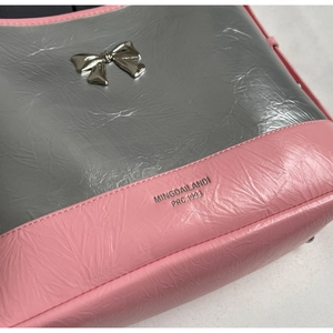 Detail of a silver metallic bow decoration on a pink and silver textured hobo shoulder bag