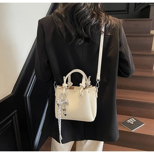 Close-up of cream bucket bag with lychee texture and silver heart charm on model
