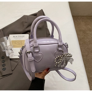 Detail of lavender mini handbag featuring heart stitching and metal bead bow charm