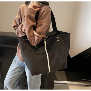 Detail of large canvas tote bag with contrast webbing and leather trim on a shoulder