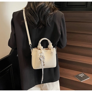 Chic cream bucket bag with lychee texture and knotted handle on a shoulder strap view