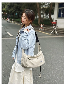 Detail of light beige nylon crossbody bag featuring side drawstring pocket and flap closure
