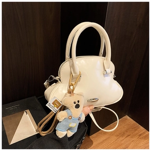 Detalle del bolso concha blanco crema en cuero sintético liso con un tierno osito