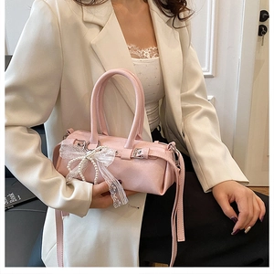 Dettaglio della borsa a cilindro rosa con fiocco in pizzo e perle indossata dal modello