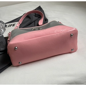 Detail view of pink and silver tote with metal studs and bow accent on textured leather