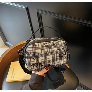 Detail of checkered crossbody bag featuring Snoopy cartoon print and black fabric strap