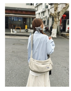 Detailed back view of a large beige nylon crossbody bag worn on a wide shoulder strap