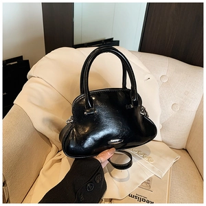 Detalle de bolso de mano en cuero encerado negro brillante con herrajes plateados