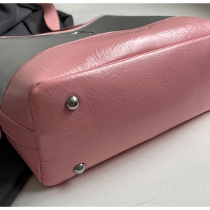 Detailed macro view of stitched pink textured faux leather bag with silver base rivets
