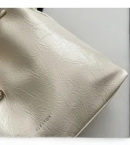 Détail du cuir crème plissé brillant et du logo de la marque CLEAROK sur le sac cabas