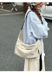 Detail of beige nylon crescent bag with side drawstring and brand logo patch