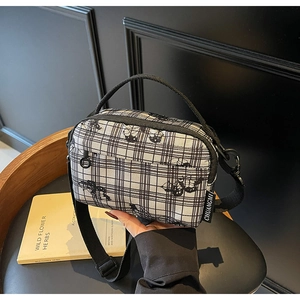Detailed view of black and white checkered canvas bag with adjustable shoulder strap