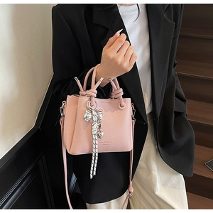 Detail of pink pebbled leather bucket bag with top handles and logo embossing