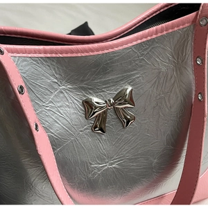 Detail of silver metallic wrinkled leather handbag with pink trim and metal bow decoration