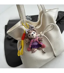 Détail du charm peluche ShellieMay avec robe violette sur un sac cabas en cuir crème