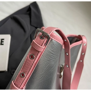 Close-up of pink leather shoulder strap with silver eyelets and buckle on a metallic bag